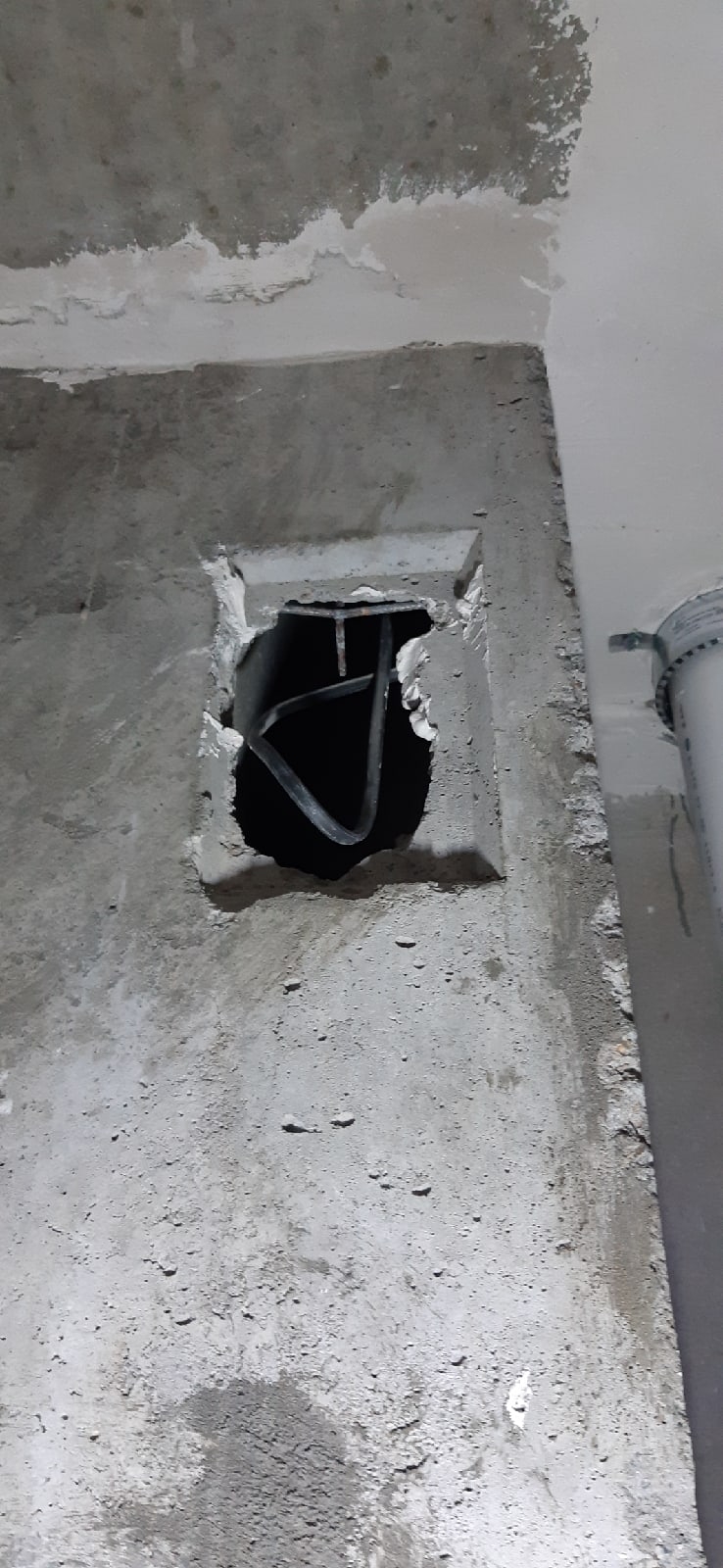 Открытое отверстие с проводами в стене рядом с инженерной трубой